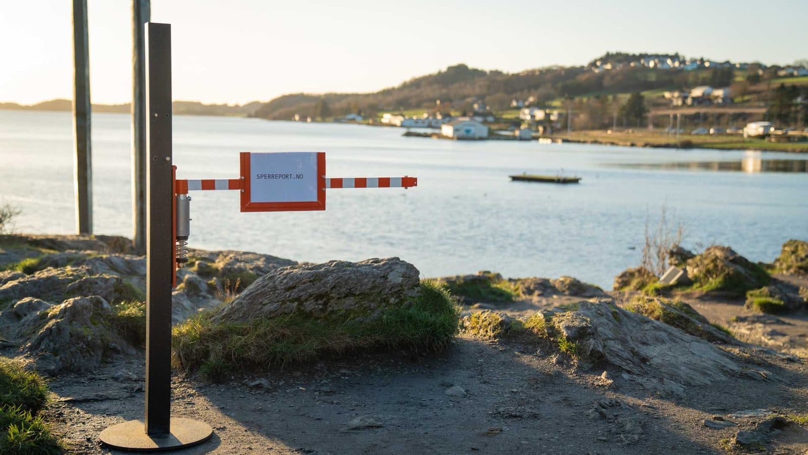 Sperreport montert på frittstående stolpe med fotplate, plassert på tvers av en sti ved fjorden
