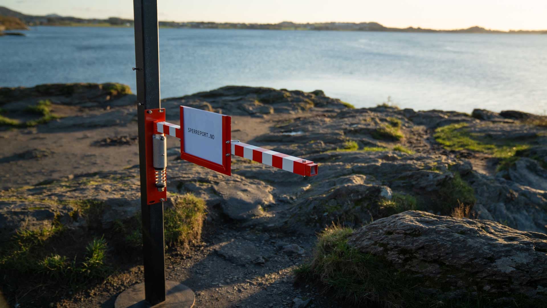Sperreport sideveis montert på stolpe på en sti langs fjorden, i lukket posisjon