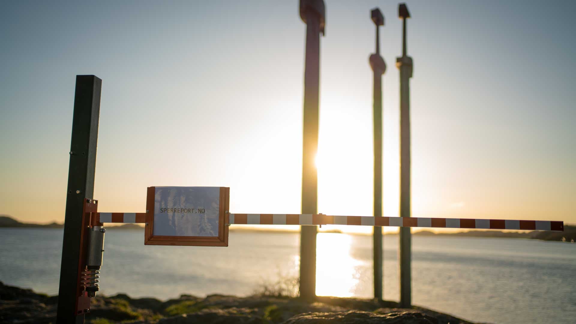 Sperreport sideveis i motlys mot solnedgangen over Hafrsfjord, med Sverd i fjell i silhuett