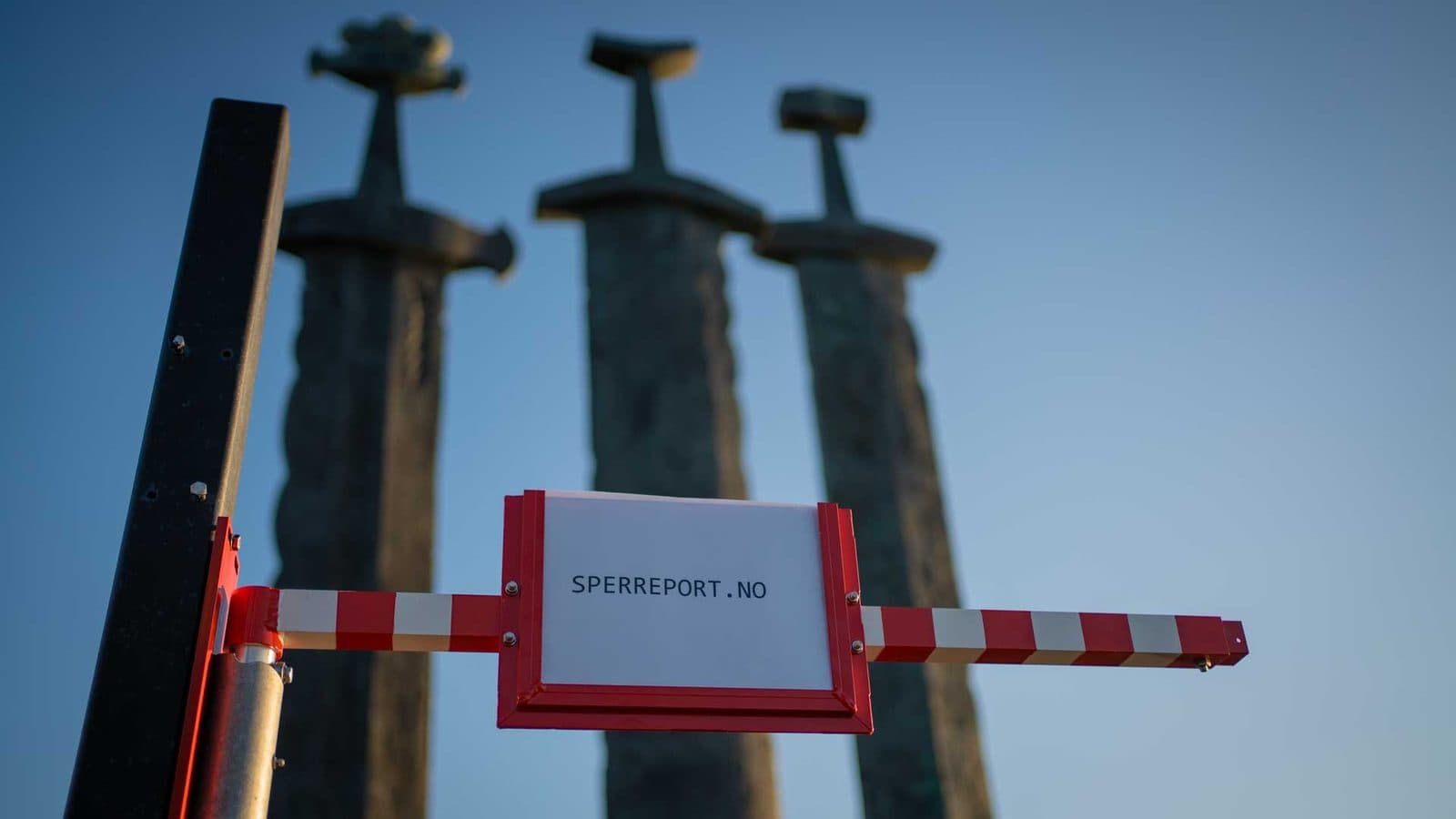 Sperreport sideveis sett nedenfra, med SPERREPORT.NO-skilt i rød skiltholder midt på den stripete teleskoparmen